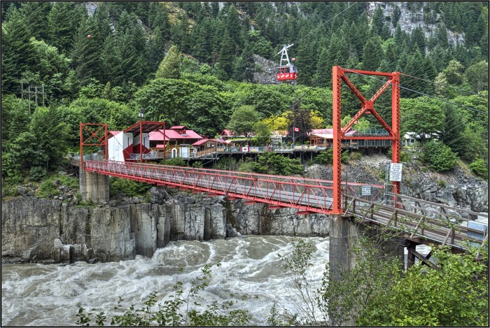 Red Suspension Bridge Over Rushing River with Gondola