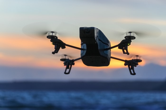 Drone flying over water at sunset