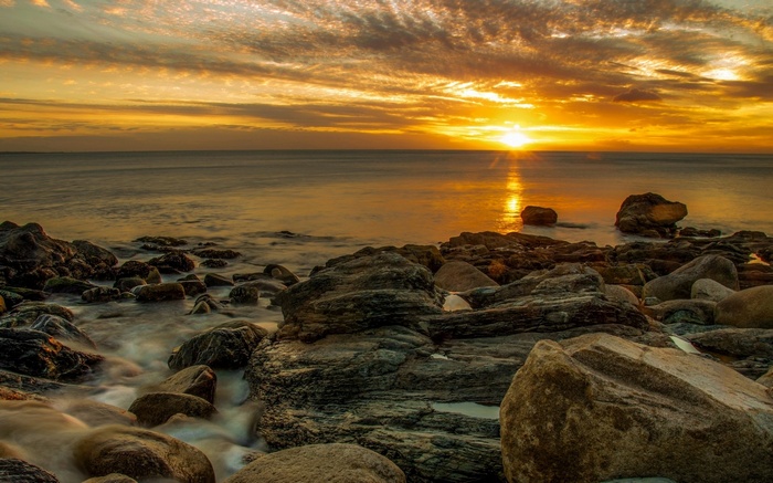 Sunset over rocky coastline with ocean waves