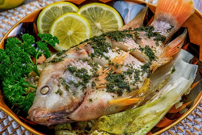 Whole baked fish with herbs, lemon, and lettuce