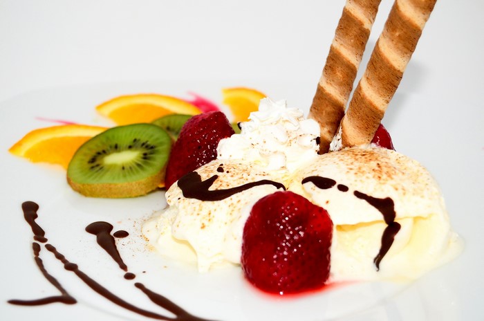 Ice cream sundae with strawberries, kiwi, and wafer rolls