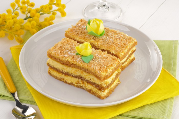 Two Napoleon cakes on a plate with yellow flowers