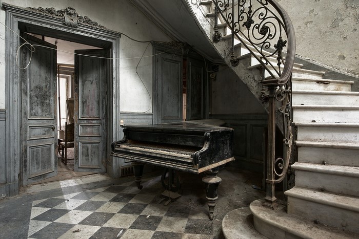 Abandoned piano in a decaying mansion hallway