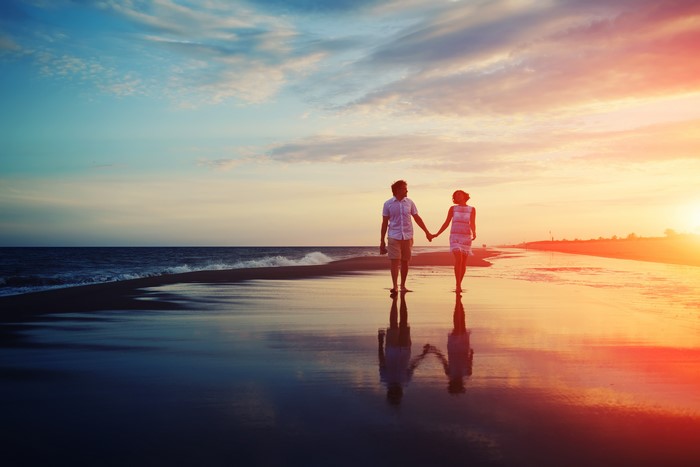 Couple walking on beach at sunset