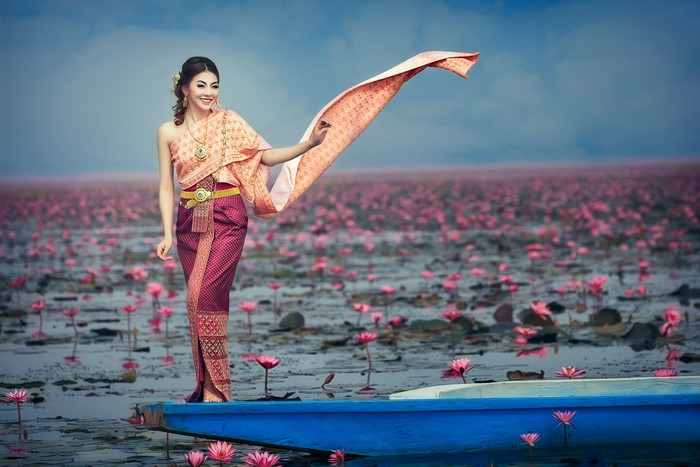 Woman in Traditional Asian Dress on a Boat with Lotus Flowers