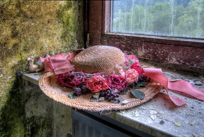 Straw hat with flowers and ribbon on windowsill