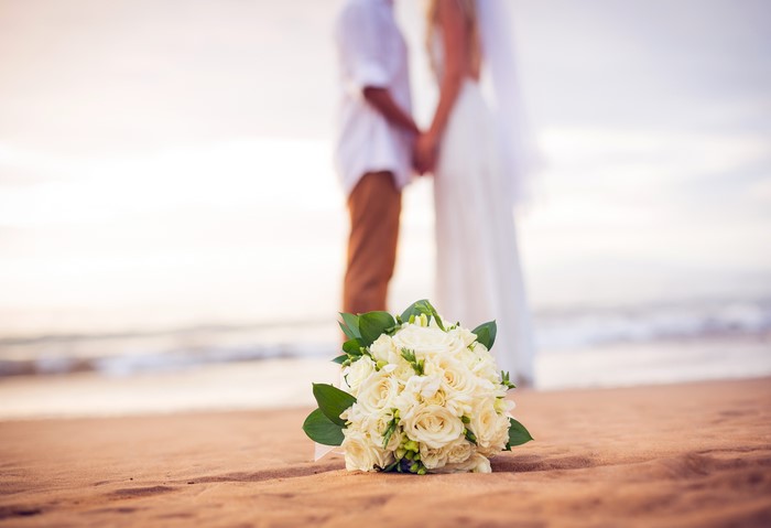 Wedding bouquet on a beach with a couple