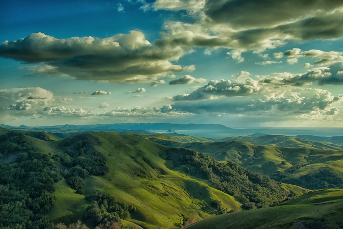 Rolling green hills and clouds over the ocean