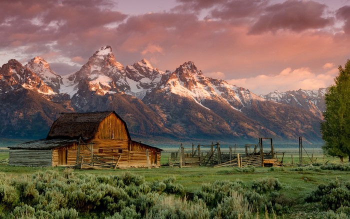 Wooden barn in front of snow-capped Teton Mountains at sunrise