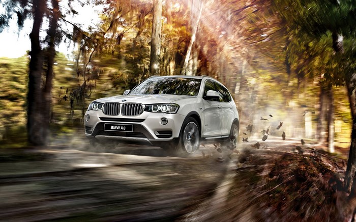 White BMW X3 driving on a dirt road