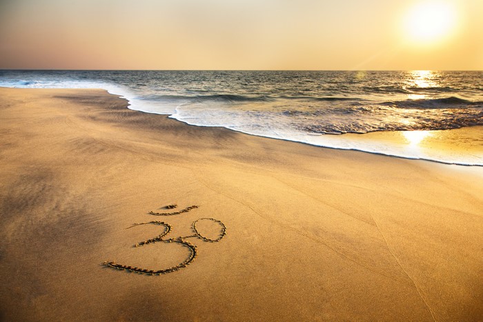 Om symbol drawn in sand on a beach at sunset