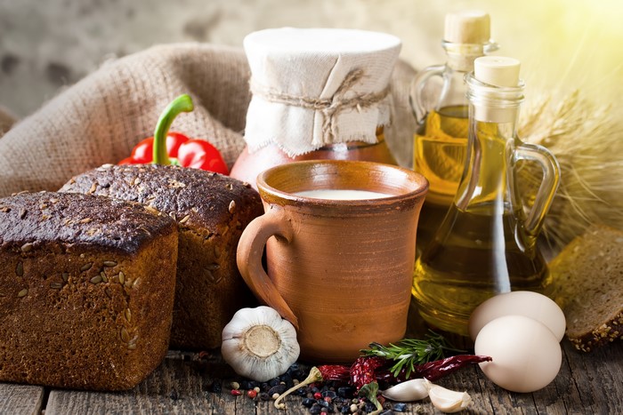 Milk in a cup with bread, eggs, and oil