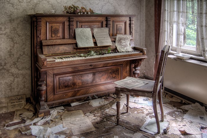 Abandoned piano and chair with scattered sheet music