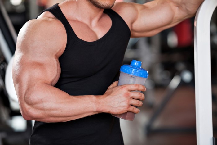 Bodybuilder holding a protein shake in a gym