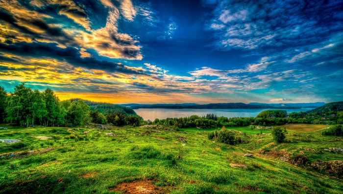 Scenic view of a lake with rolling green hills and dramatic sky