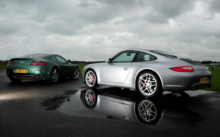 Aston Martin V8 Vantage and Porsche 911 on wet asphalt