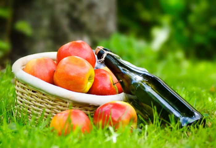 Apples in a basket with a bottle on grass