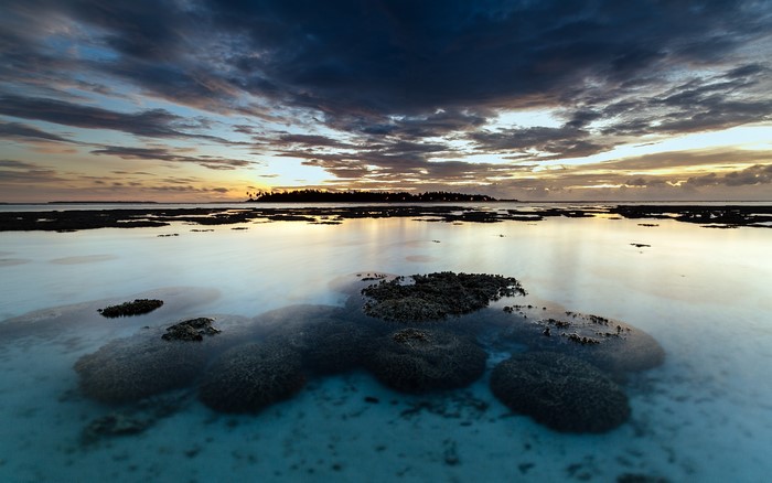 Coral reef at sunset with island in the distance