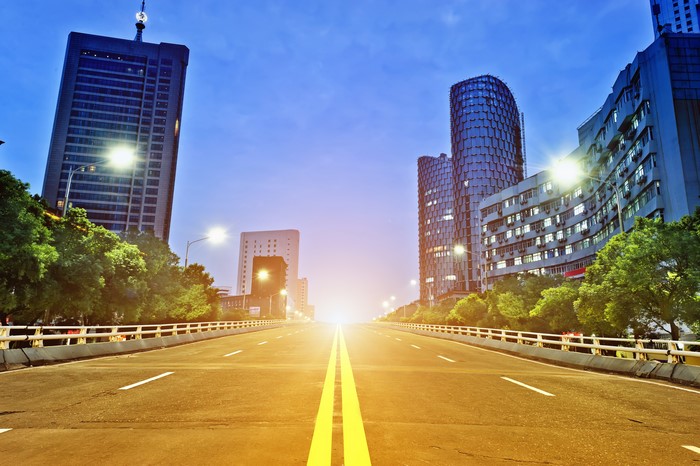 Road leading to modern city buildings at dusk