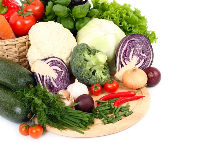 Assortment of fresh vegetables including cabbage, broccoli, tomatoes, and onions