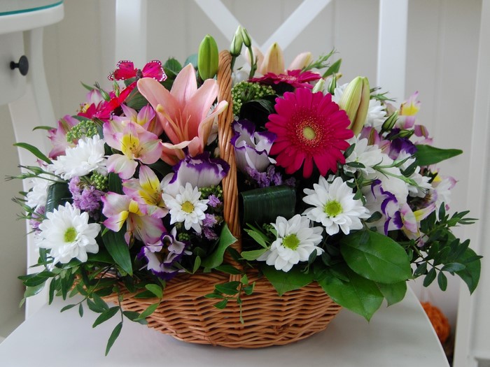 Flower bouquet with gerberas, chrysanthemums, lilies in a wicker basket