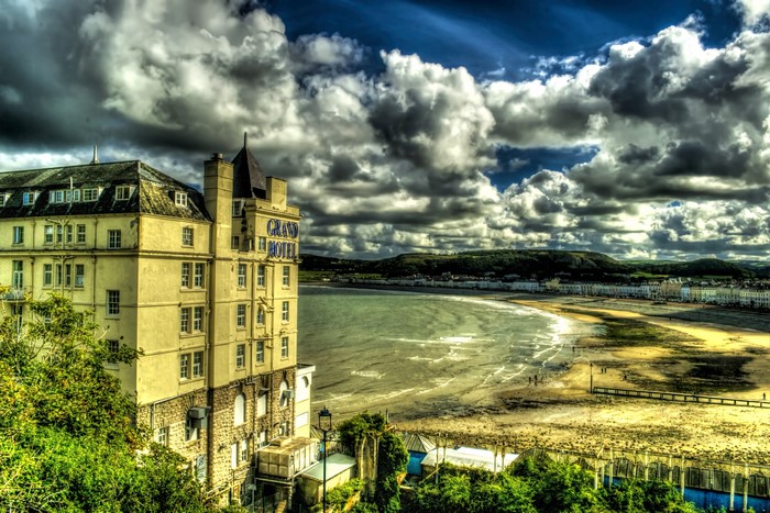 The Grand Hotel in Llandudno, Wales, with a beach and cloudy sky
