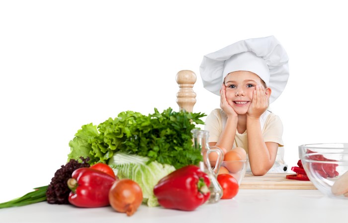 Little girl in chef uniform with vegetables