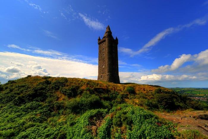 Scrabo Tower on a grassy hill under a blue sky
