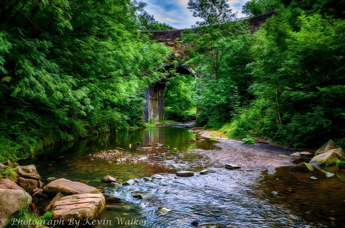 Stone bridge over a river in a forest in Oldham, England