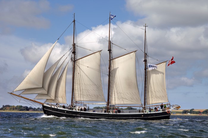 Schooner sailing on a wavy sea with Danish flag