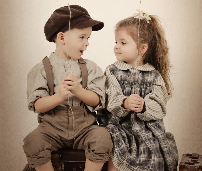 Boy and girl in vintage clothing holding string
