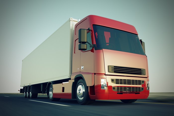 Red semi-truck with a white trailer on a road