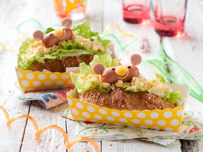 Two hot dogs decorated as animals on a table