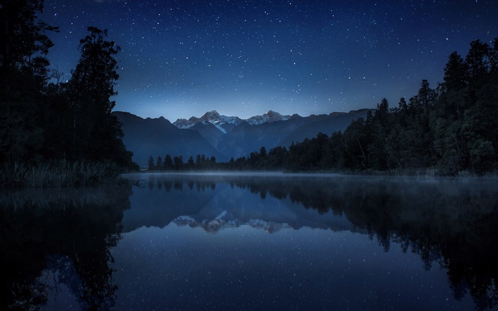 Starry night over a misty lake and mountains