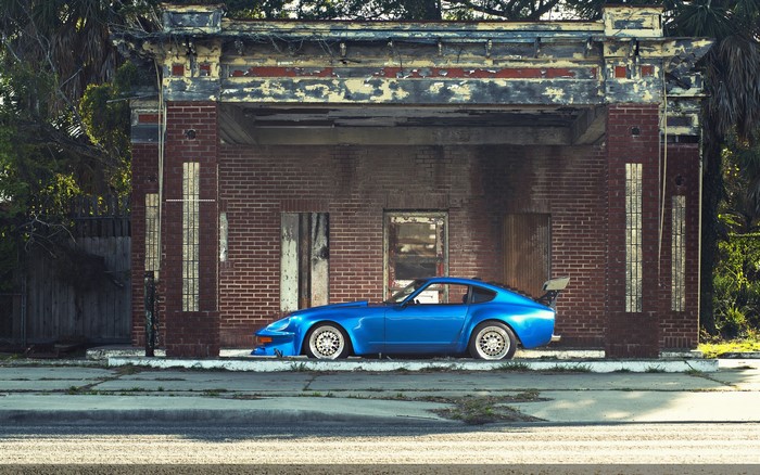 Blue Datsun 240Z Fairlady parked in front of abandoned building