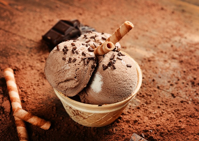 Chocolate ice cream in a cone with wafer sticks and chocolate chunks
