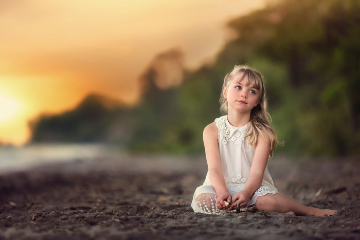 Girl sitting on a beach at sunset