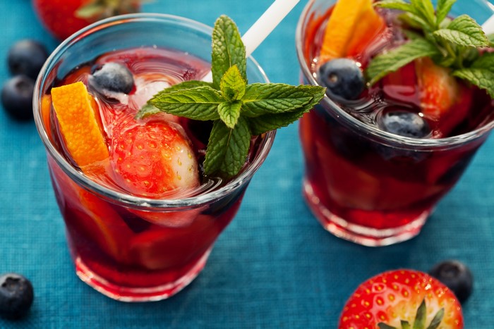Two glasses of fruit infused drinks with strawberries and blueberries