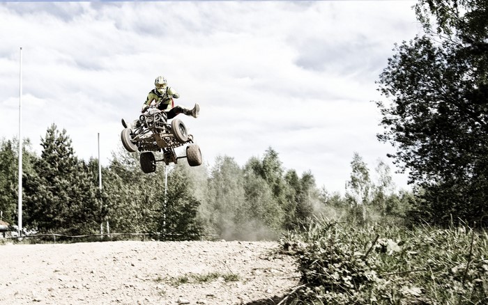 Quad bike rider jumping over a dirt track