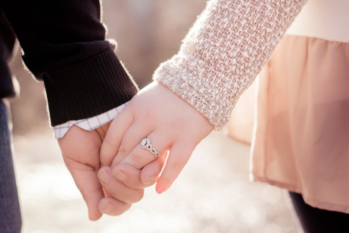 Couple holding hands with engagement ring