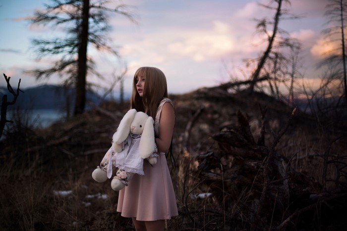 Girl holding a stuffed bunny in a forest
