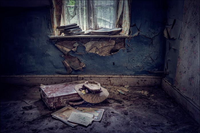 Abandoned room with old suitcase and hat by window