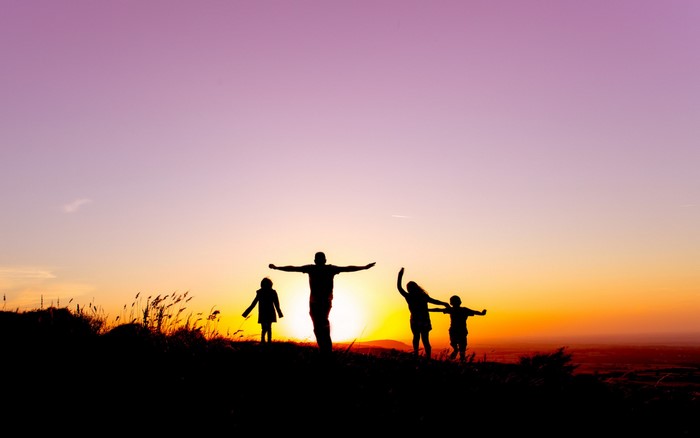 Family silhouetted against a sunset sky