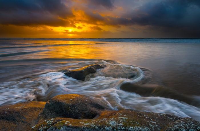 Sunset over Hellesto Beach, Stavanger, Norway with waves and stones