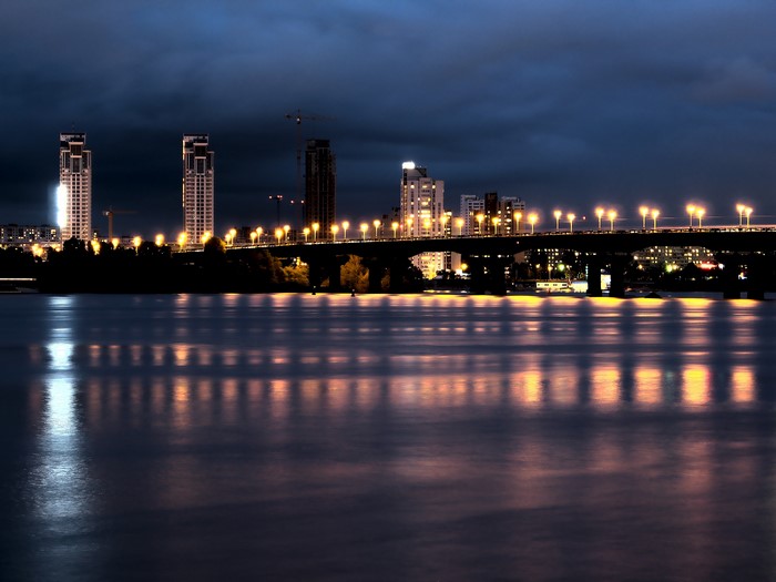 City skyline with bridge and river at night