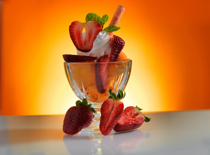 Orange ice cream sundae with strawberries and whipped cream