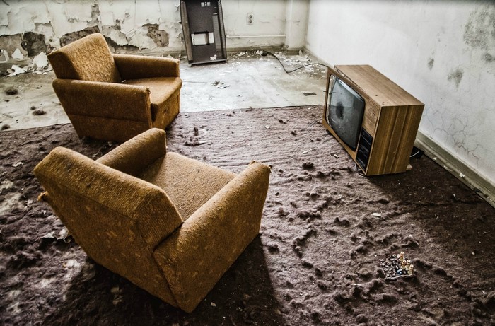 Two armchairs and an old TV in a derelict room