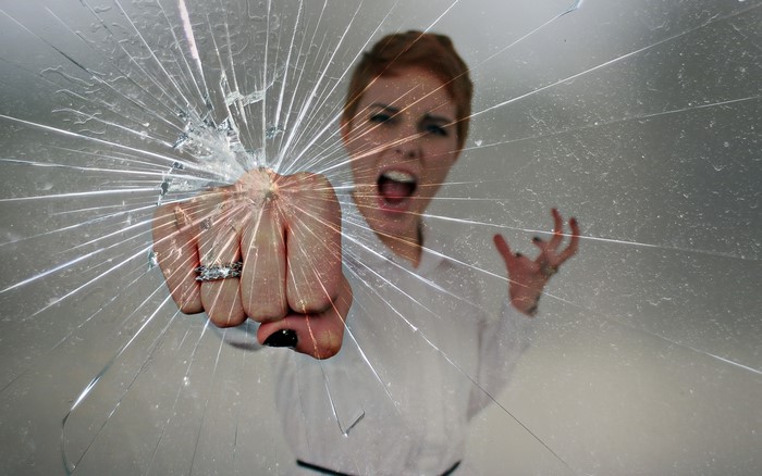 Woman punching through cracked glass