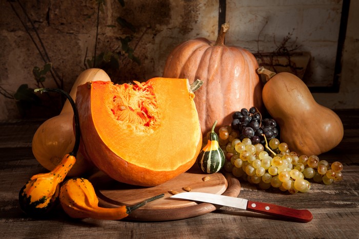 Autumn still life with pumpkins, grapes, and knife