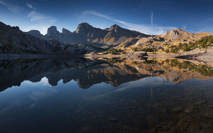 Mountain lake reflecting rocky peaks under a blue sky